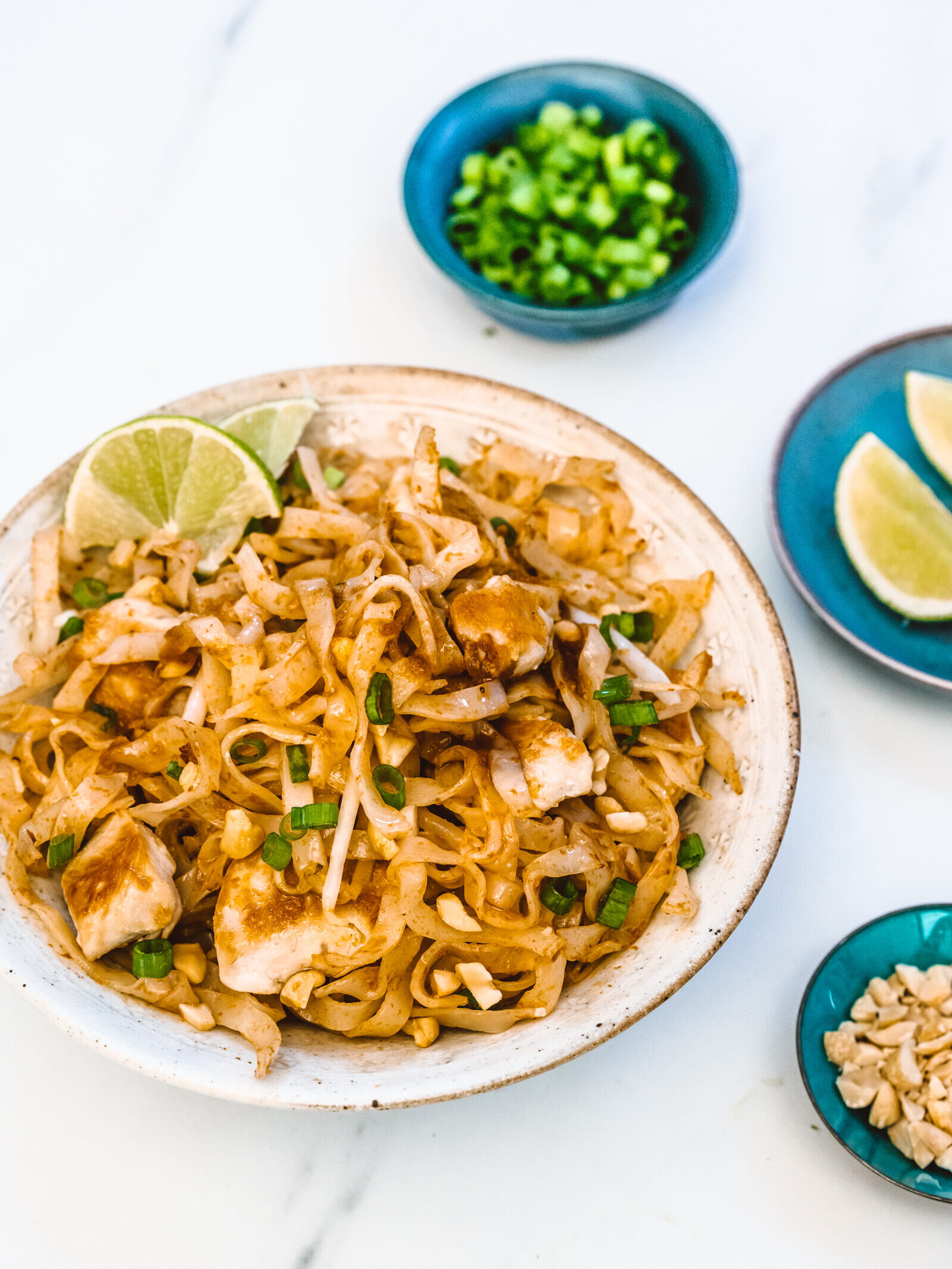 Easy chicken pad thai on table with garnishes